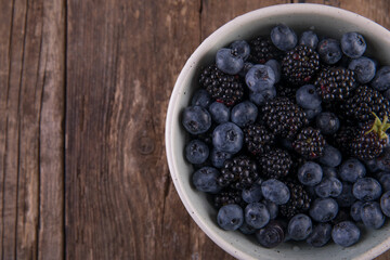 Ripe black blackberries and blue blueberries on a wooden table