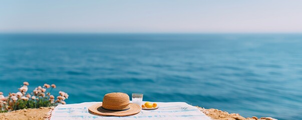 Coastal table setup with a hat, drink, and lemon against a serene ocean backdrop, perfect for a relaxing summer day by the sea.