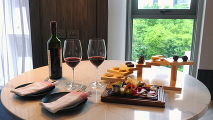 Elegant dining setup with red wine, artisan cheese, and charcuterie board on marble table by window in modern home, perfect for romantic evening or special occasion, Wine and Fine Dining.