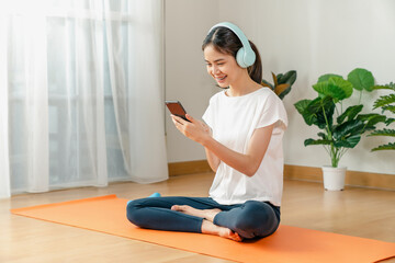 Young Asian woman sitting on the phone after finishing exercise.