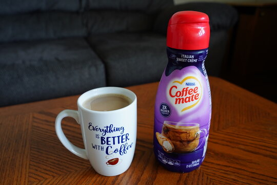 A bottle of Nestle Coffee-Mate creamer next to a coffee cup. 