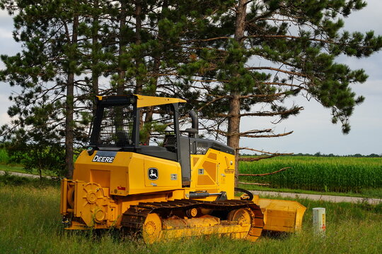 A Yellow John Deere bulldozer construction vehicle sits at the roadside.