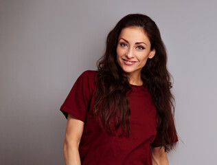 Fototapeta premium Happy smiling casual beautiful woman posing in dark red cotton t-shirt on blue studio background. Closeup