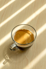 A cup of coffee is on the wooden table.