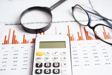 Eyeglass with calculator on chart graph paper. Finance, account, statistic, investment data economy, stock exchange business.