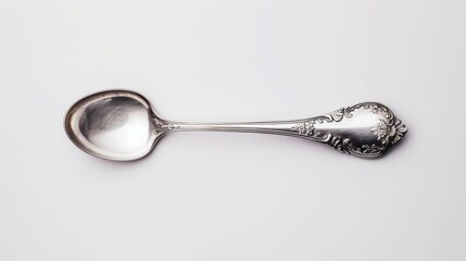 A polished silver spoon with intricate floral engravings, set against a plain white background, ample space for copy text