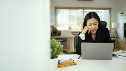 Portrait of charming young businesswoman working on laptop in home office