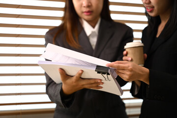 Cropped shot of young business colleagues discussing project and reviewing papers during a coffee break