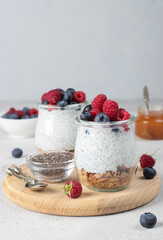 Chia pudding with muesli, fresh berries, honey and natural yogurt on wooden board. Healthy...