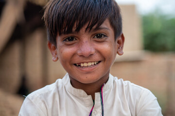 A young boy with a cheerful smile stands in a temporary camp.