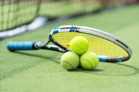 Tennis racket and balls on green grass. Sports equipment
