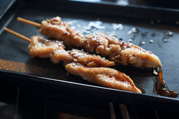 Wonderful view of Teriyaki chicken skewers on black plate and soy sauce