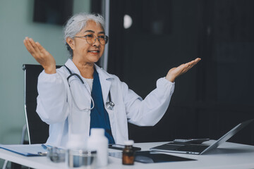 Confident female doctor sitting with laptop at desk in clinic