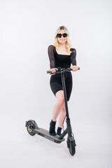 Fototapeta premium Woman ride e-scooter looking camera isolated on white background studio portrait. Lifestyle concept