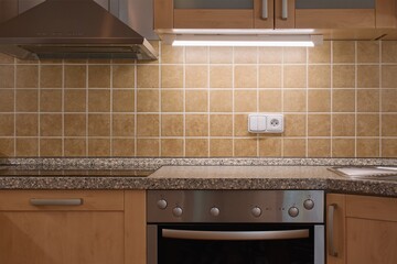 Classical kitchen interior. Brown tiles, oven and kitchen extractor fan.