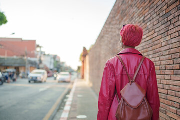 Gen z girl leather fashion with punk Asian woman tourist of local city Southeast Asia travel trendy pink hairstyle young female punk traveler walking around in town