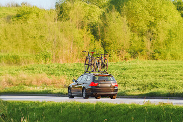 Family car with bikes on roof rack on a sunny country road trip