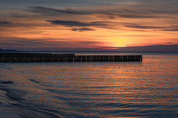 Naklejka premium View of sand beach with wooden breakwaters on the Baltic Sea coast on sunset in Zelenogradsk. Russia