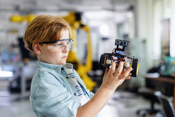 Portrait of schoolboy building robotic car in after-school robotics club. Children learning robotics in Elementary school. Science for kids.