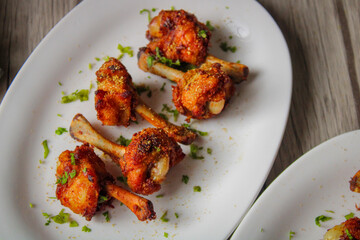 Chicken lollipop deep fried in oil. Later garnished with green coriander and onion.