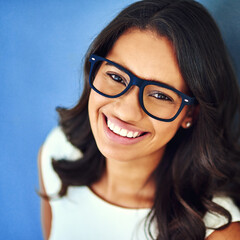 Portrait, confidence and woman with glasses in studio for optometry, vision or prescription lens on blue background. Refraction, wellness and business person with for spectacles, eyewear or top view