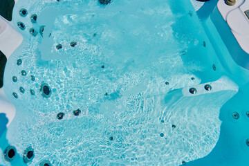 Close-up shot bubbling water in hot tub with headrests. Blue water in jacuzzi for relaxing and...