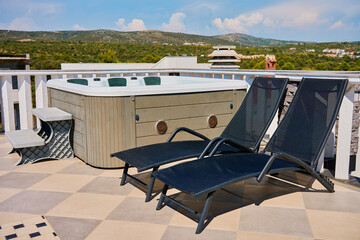 Sunny rooftop deck with hot tub and two black lounge chairs. Jacuzzi with beautiful natural view....