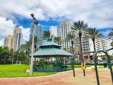 Sunny Isles Beach, Florida - Town Center Park with skyscrapers in the background, featuring a cozy gazebo and playground swings on a sunny day.