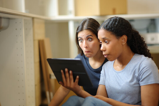 Surprised roommates checking tablet reforming kitchen