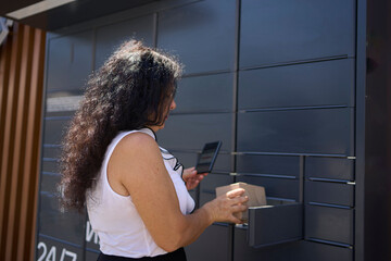 a  woman picks up a parcel from a post terminal using a mobile application