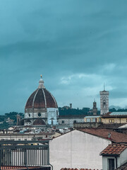 Fototapeta premium A large dome building with a clock tower in the background. The sky is cloudy and the buildings are white