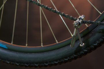 The mechanic uses a special tool to change the chain on the bike. chain riveter on a black background. Chain tool. Mountain bike repair and maintenance