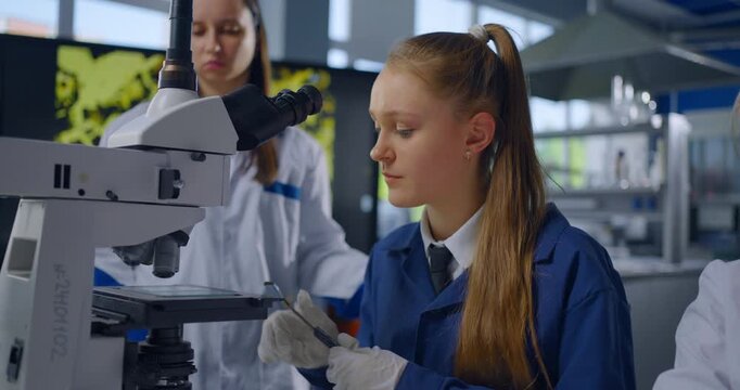 Portrait Of Smart Young Student Girl Examining Chemical Reagents With Microscope In Classroom