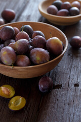 Fresh plums on plate over dark stone background