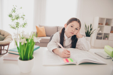 Photo portrait of cute adorable girl unhappy tired write textbook homework remote lesson education from home indoors