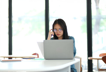 Fototapeta premium A woman is sitting at a table with a laptop in front of her