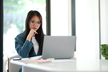 A woman is sitting at a desk with a laptop in front of her