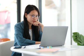 A woman is sitting at a desk with a laptop open in front of her