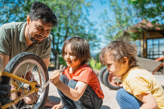 Father and sons repairing old bicycle in back yard