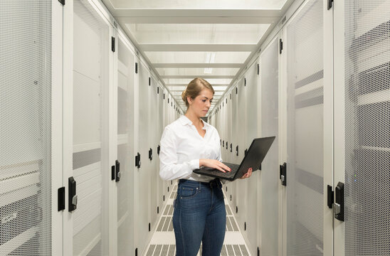 Engineer using laptop and standing in server room