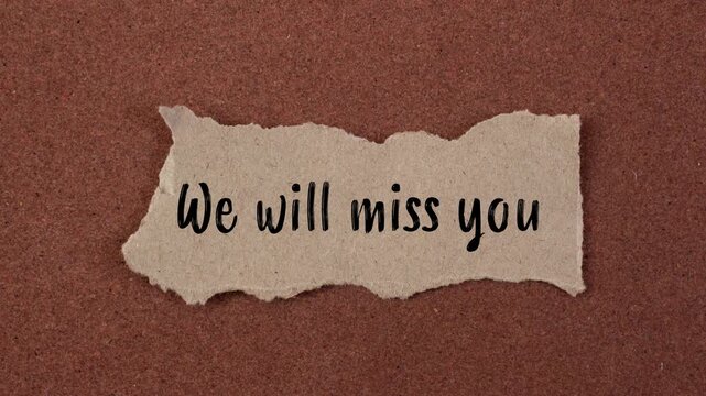 We will miss you message writing on ripped torn paper piece on brown background