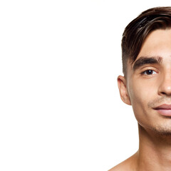 Fototapeta premium Cloe -up portrait of young man with neatly styled hair and well-groomed features, focusing on one half of his face against white studio background. Concept of beauty, care, cosmetology, wellness. Ad