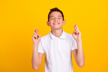 Photo of good mood dreamy boy wear white t-shirt closed eyes fingers crossed emtpy space isolated...