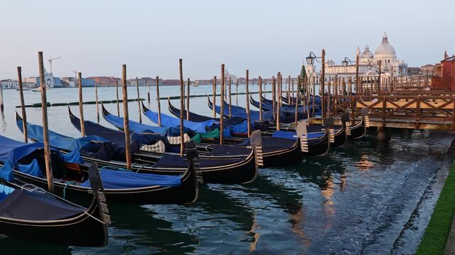 Gondolas in the Venetian Lagoon at sunrise in city of Venice, Italy. Traditional Venetian rowing boats at Riva degli Schiavoni waterfront.