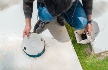 Cleaning and maintenance of the swimming pool skimmer basket. Person cleaning pool filter skimmer...