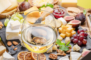 Glass of white wine with variety of sliced cheeses.