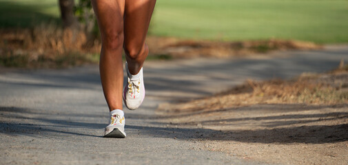 Young fitness woman legs, running in the city public park in morning