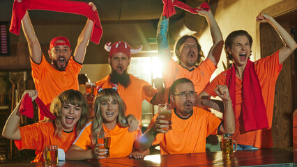 Enthusiastic fans, women and men, sitting at bar counter shouting, screaming supporting their favorite football team and drinks beer. Concept of friendship, soccer fan, championship, celebration. Ad