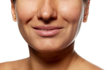 Cropped photo of woman's face with slight smile against white studio background. Face lifting and mimic wrinkles. Concept of facial care, lifting, spa procedures, anti-aging, surgery.