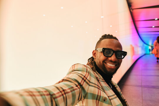 Smiling businessman taking selfie near illuminated wall
